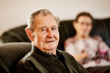 Senior sitzt zusammen mit einer Seniorin zuhause im wohnzimmer
