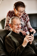 Senior, Seniorin, Seniorenpaar surft gemeinsam auf einem Smarphone im Internet