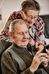 Senior, Seniorin, Seniorenpaar surft gemeinsam auf einem Smarphone im Internet