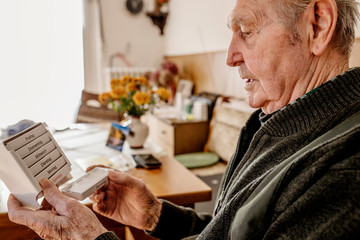 Senior nimmt seine Tabletten ein aus einer Medikamentenbox