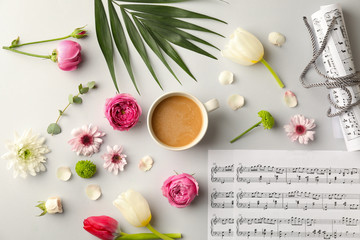Fototapeta na wymiar Composition with cup of coffee, beautiful flowers and music notes on light background