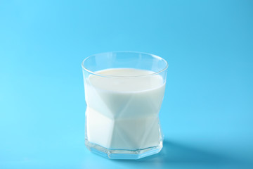 Glass of tasty milk on color background