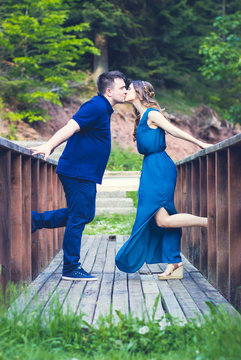 Outdoor photo, young, beautiful couple kissing on the wooden bridge