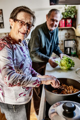 Seniorenpaar steht in der Küche am Herd und kocht