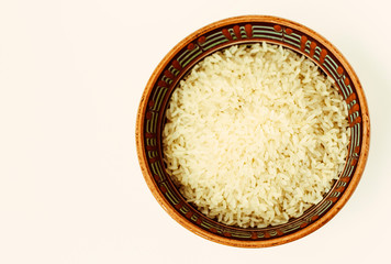 Ceramic brown bowl with long rice on white background top view.