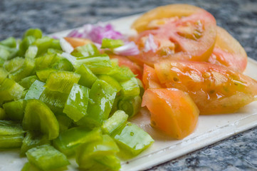 purple Onion, red tomatoes and green peppers cut together for salad preparation
