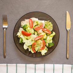 healthy salad, vegetable, tomatoes, cucumbers, iceberg, Cutlery, kitchen towel, grey background. Copy space. Vegetarian