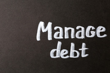 Fototapeta premium Manage debt financial planning with white chalk text on dark black background for business strategy