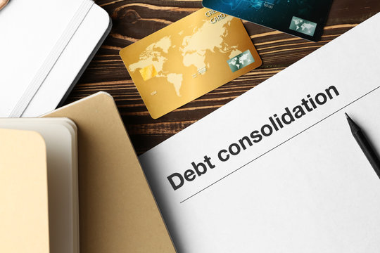 Paper With Text DEBT CONSOLIDATION, Notebooks And Credit Cards On Table