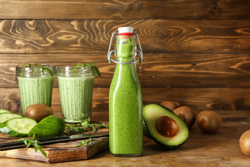 Bottle and glasses of healthy juice with ingredients on wooden table