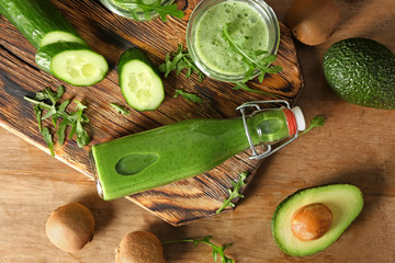 Bottle and glass of healthy juice with ingredients on wooden table