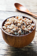 Boiled buckwheat in a wooden bowl on the village table.