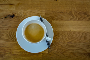 Tasse Kaffee auf Holztisch am Arbeitsplatz Homeoffice mit Kugelschreiber 