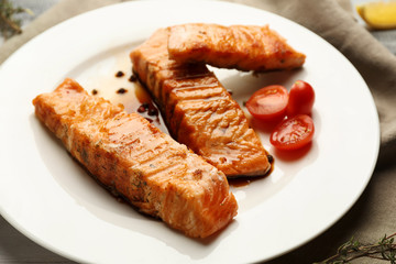 Pieces of tasty grilled salmon with tomatoes on plate