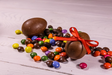 Chocolate easter eggs and multicolored candies on wooden table