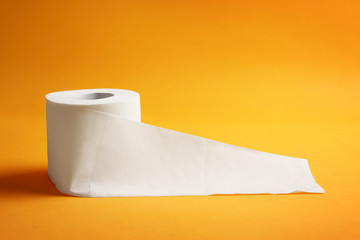 Roll of toilet paper on color background