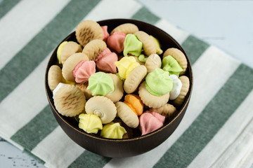 Sugar cookies on a wooden bowl isolated on colorful napkin background.