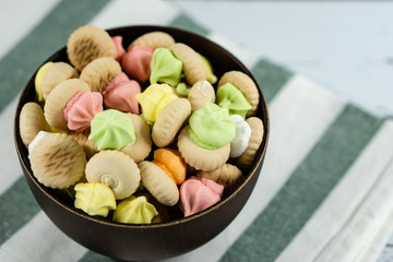Sugar cookies on a wooden bowl isolated on colorful napkin background.