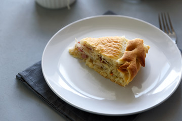 Slice of homemade sauerkraut pie on gray wooden table. Cabbage cake tradition russian food