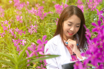 Happy researcher botanical research orchid wearing a white cap and her hand holding a pen and...