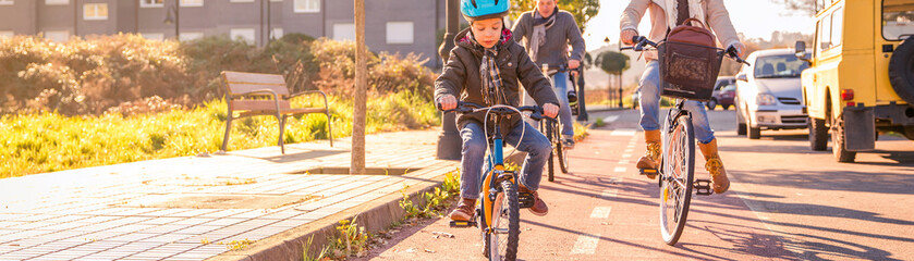 Happy family with a child riding bicycles by the city on a sunny winter day