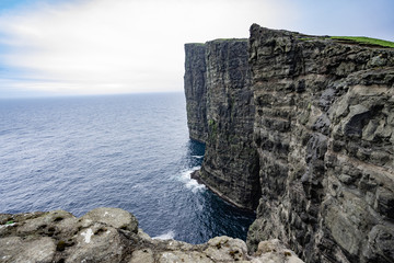 Fototapeta na wymiar Amazing view of slave mountains of Tralanipan steep cliff in Vagar island, Faroe Islands, Denmark north Atlantic ocean, best destination for hiking, stunning sea stack with deep blue water