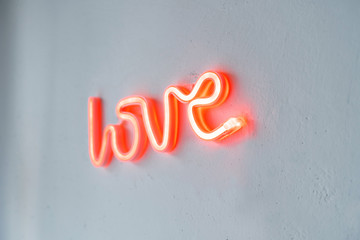 Red Neon Love Sign on a white wall. Close view with selective focus.
