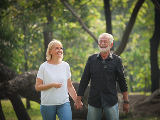 Two happy seniors retirement Man and woman are walking  and talking in park