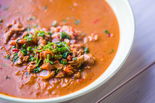 Rindfleischeintopf oder Gulaschsuppe mit Fleischst&uuml;cken in roter Tomaten sauce