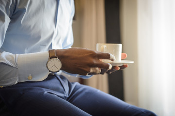 Obraz na płótnie Canvas Businessman with watch on his wrist holding mug with morning espresso coffee