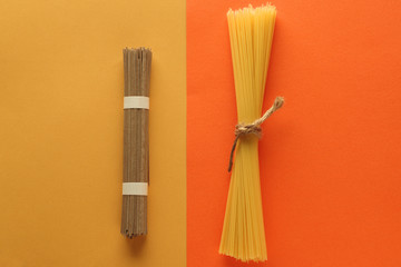 buckwheat noodle spaghetti and wholegrain spaghetti on a bright yellow and orange background. Top...