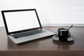 Laptop with empty blank screen on wooden tabletop with modern blur kitchen background. Work at home. Freelance. E-learning.