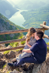 Naklejka na ściany i meble Outdoor photo of young, beautiful couple being affectionate to each other, hugging and kissing at beautiful location, vantage point for Tara river
