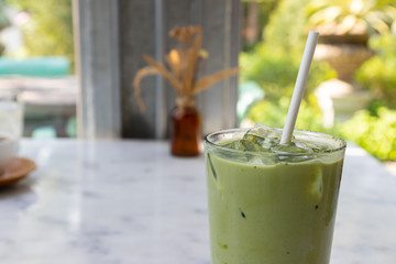 white paper straw in Iced Matcha Latte Tea with Milk on white marble table in coffee shop. concept : reduce plastic,  eco-friendly  Drinking straw, healthy beverage.