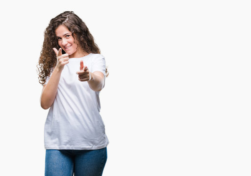 Beautiful brunette curly hair young girl wearing casual t-shirt over isolated background pointing fingers to camera with happy and funny face. Good energy and vibes.