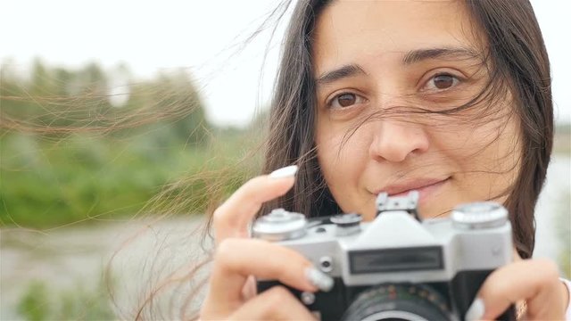 A beautiful girl holds a camera and takes pictures. Close-up