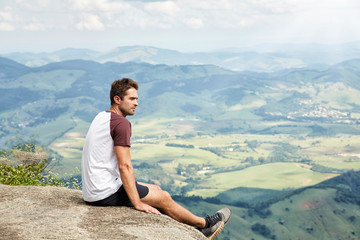 Fototapeta na wymiar Handsome sportsman enjoying view from cliff edge