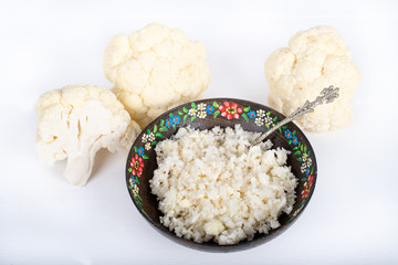 Paleo organic vegetarian food cauliflower rice in a floral rustic bowl, on white background