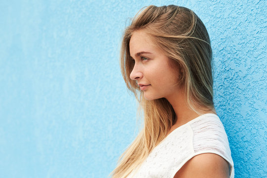 Profile of pretty girl against blue wall