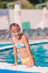 Beautiful little girl having fun near an outdoor pool