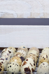 Quail eggs. They lie in a plastic container next to a wooden box.