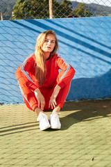 Athlete in red sport fashion, sitting in sports court