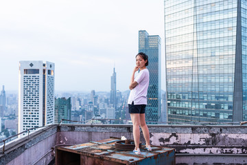 Young woman looks out over the city at the top of the building