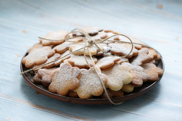 Original cookies biscuits sprinkled with powdered sugar on a plate of clay on a blue wooden background