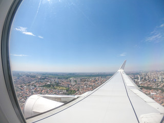 View from airplane window over airplane wing - flying over the city - travel concept