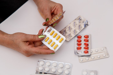 Concept for medicine. The hands of an elderly woman choose the right medicine among different drugs.