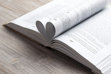 Heart shape from book pages on contrast wooden background