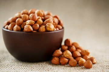 Peeled hazelnuts in a wooden, dark brown cup on a burlap cloth. Super Food, Raw.