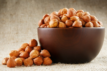 Peeled hazelnuts in a wooden, dark brown cup on a burlap cloth. Super Food, Raw.