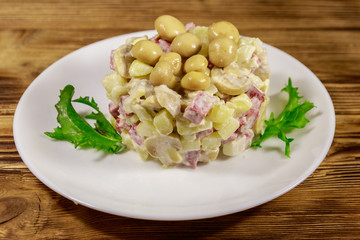Potato salad with marinated mushrooms, sausage, onion and mayonnaise on wooden table